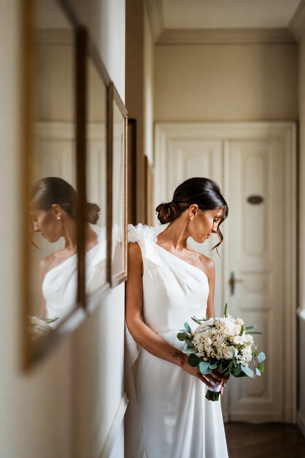 Sposa con bouquet riflessa in uno specchio in un corridoio luminoso
